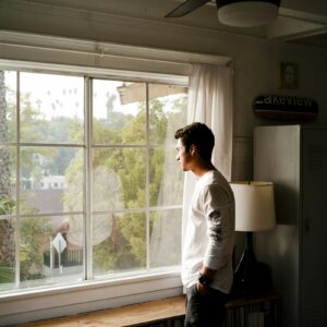 Man looking out a window, thinking about ADHD and self-medicating